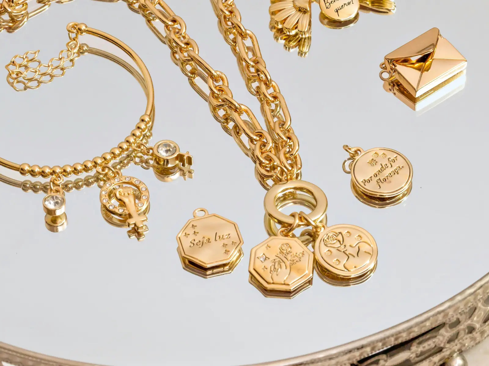 A collection of gold jewelry pieces on a mirror tray — representing the timeless connection between gold, love, and eternity across every culture on earth